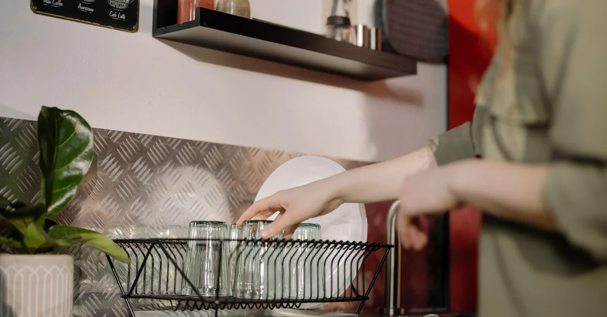 Une femme arrangeant des verres propres dans une cuisine moderne, mettant en avant l'organisation domestique.